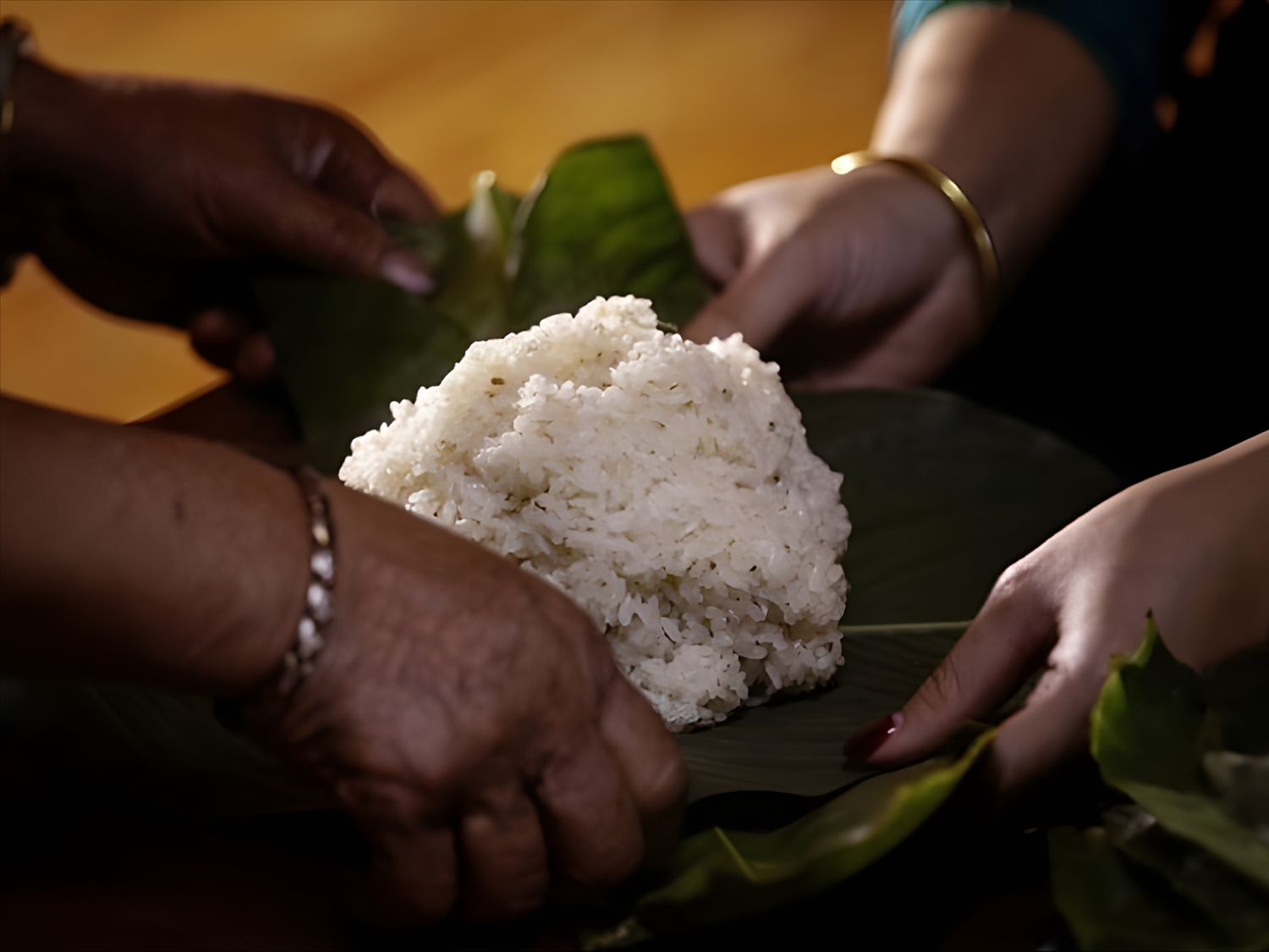 After cooking, the sticky rice is fanned to cool and then wrapped into small, square packages in banana leaves to offer to ancestors