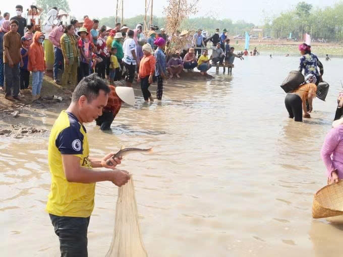 Một người dân bắt được cá trong bàu nước tại lễ hội.