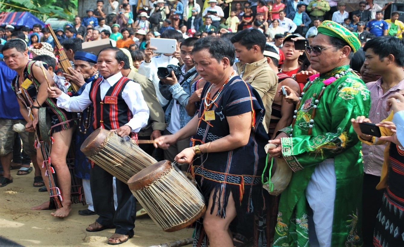Village older Briu Thien (second from the left, wearing a red striped shirt) is playing the drums during a Co Tu festival.