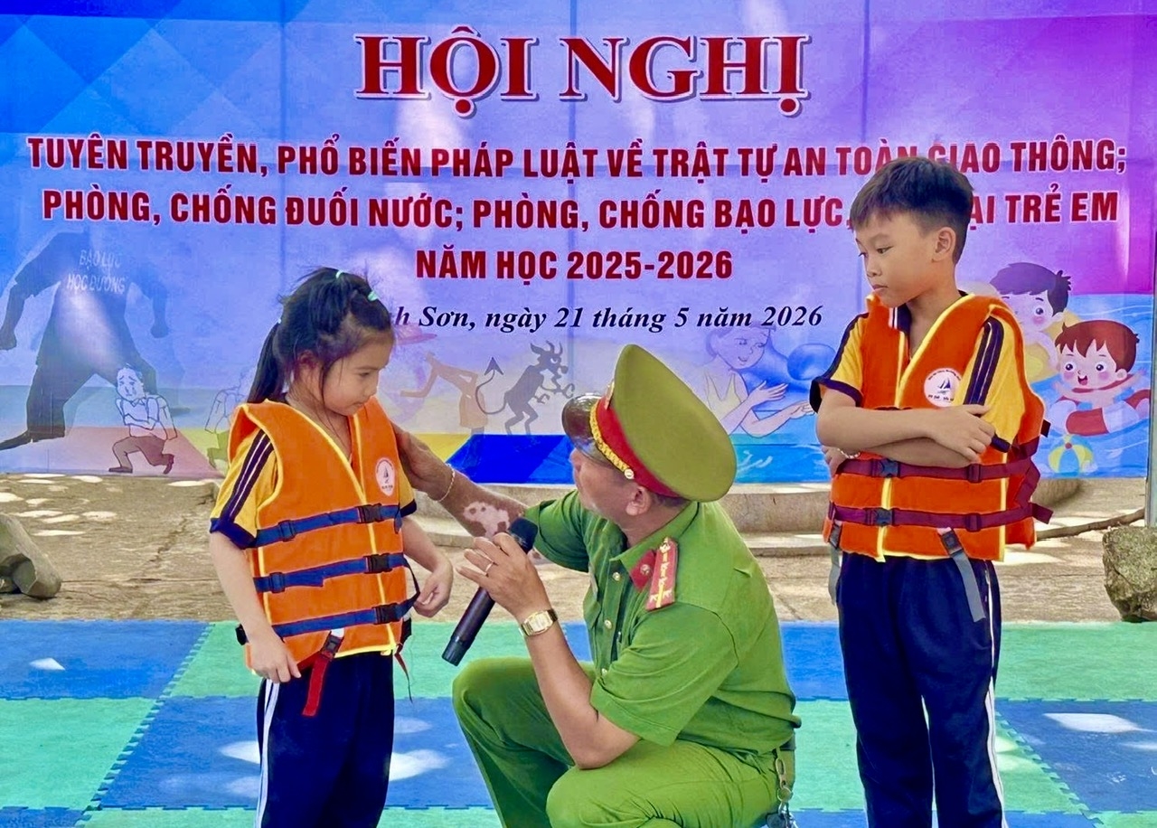 Công an xã Khánh Sơn hướng dẫn học sinh mặc áo phao đúng cách.
