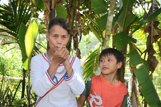 Ho Thi De is teaching her grandchild to play the A Map flute