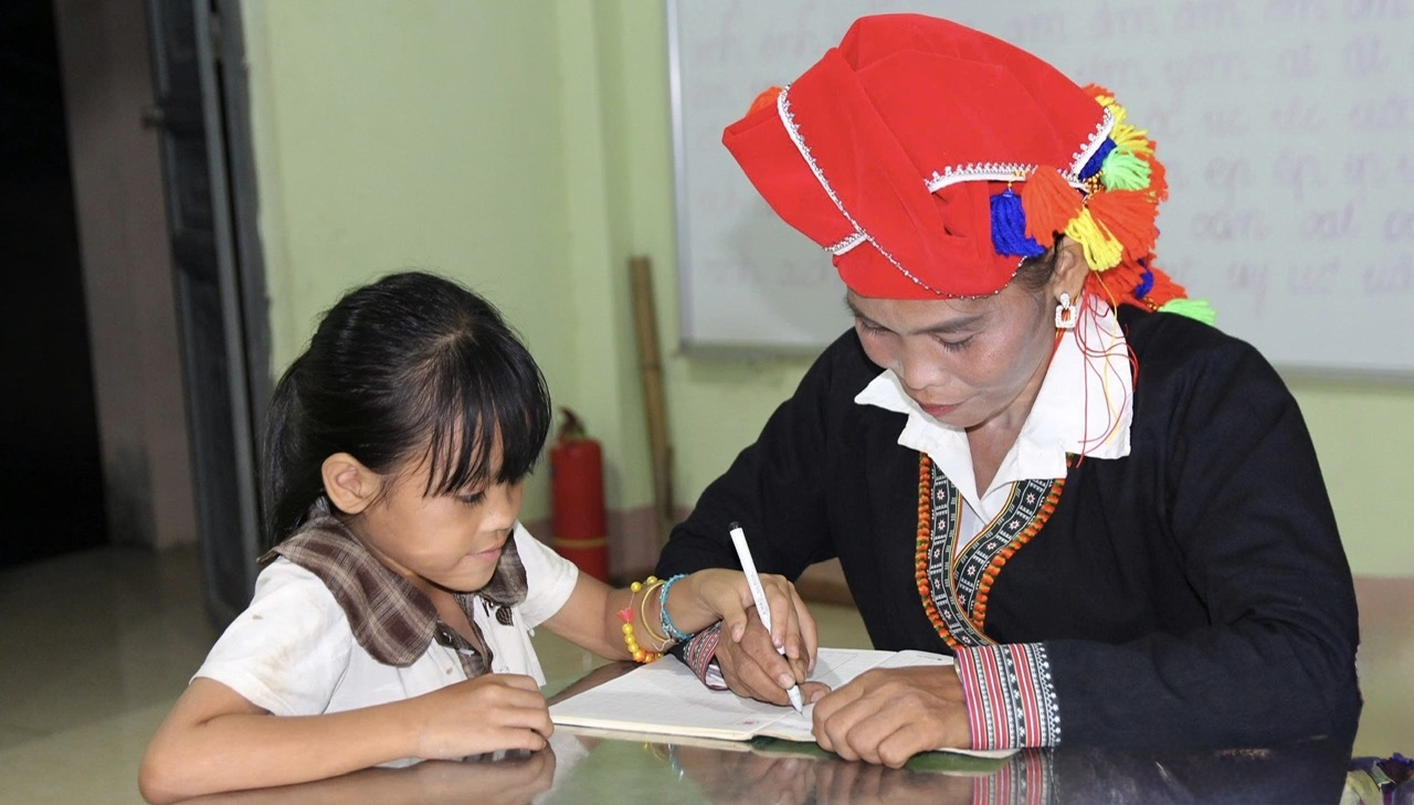 Cô con gái nhỏ kiên nhẫn hướng dẫn mẹ tập viết từng con chữ trong lớp học xóa mù chữ ở xã Bảo Hà (Lào Cai), viết tiếp giấc mơ học tập còn dang dở và lan tỏa tinh thần hiếu học trong mỗi gia đình vùng cao