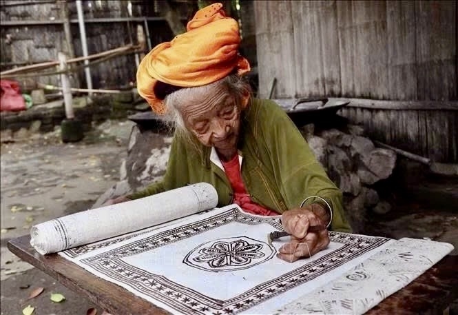 Nghệ nhân Sùng Thị Cỏ, gần 100 tuổi, thực hiện kỹ thuật vẽ hoa văn bằng sáp ong trên vải lanh truyền thống của người Mông ở xã Lùng Tám (Tuyên Quang)