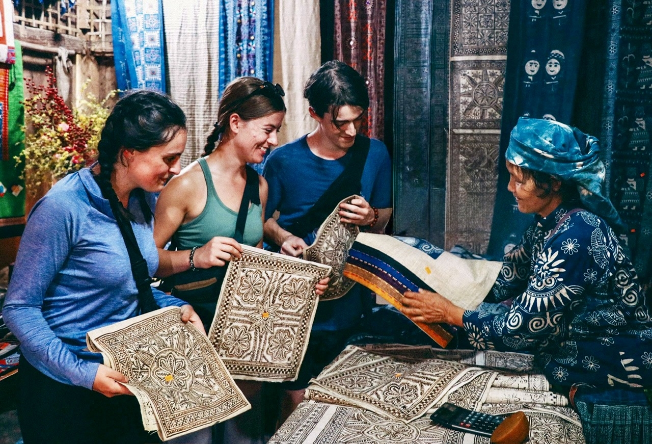 Du khách nước ngoài thích thú khám phá các sản phẩm dệt lanh truyền thống của đồng bào Mông ở Lùng Tám