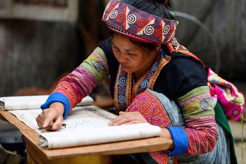 Người phụ nữ Mông tỷ mỉ vẽ sáp ong lên nền vải, tạo nên những hoa văn đặc trưng cho sản phẩm dệt truyền thống của dân tộc Mông