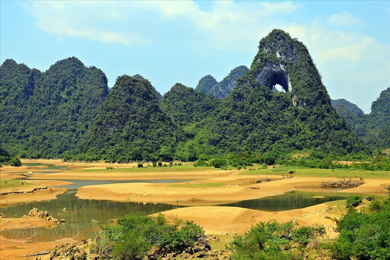 Và điểm đặc biệt nhất của Mắt Thần Núi chính là lỗ thủng khổng lồ trên sườn núi. Lỗ thủng này có đường kính khoảng 50m và cao khoảng 30m, tạo nên cảm giác như một con mắt của núi đang dõi theo mọi thứ xung quanh. Từ trên đỉnh núi, du khách trong nước và quốc tế có thể ngắm nhìn toàn cảnh khu vực này, bao gồm những ngọn núi đá vôi hùng vĩ, những cánh đồng lúa xanh mướt và những ngôi làng bình yên