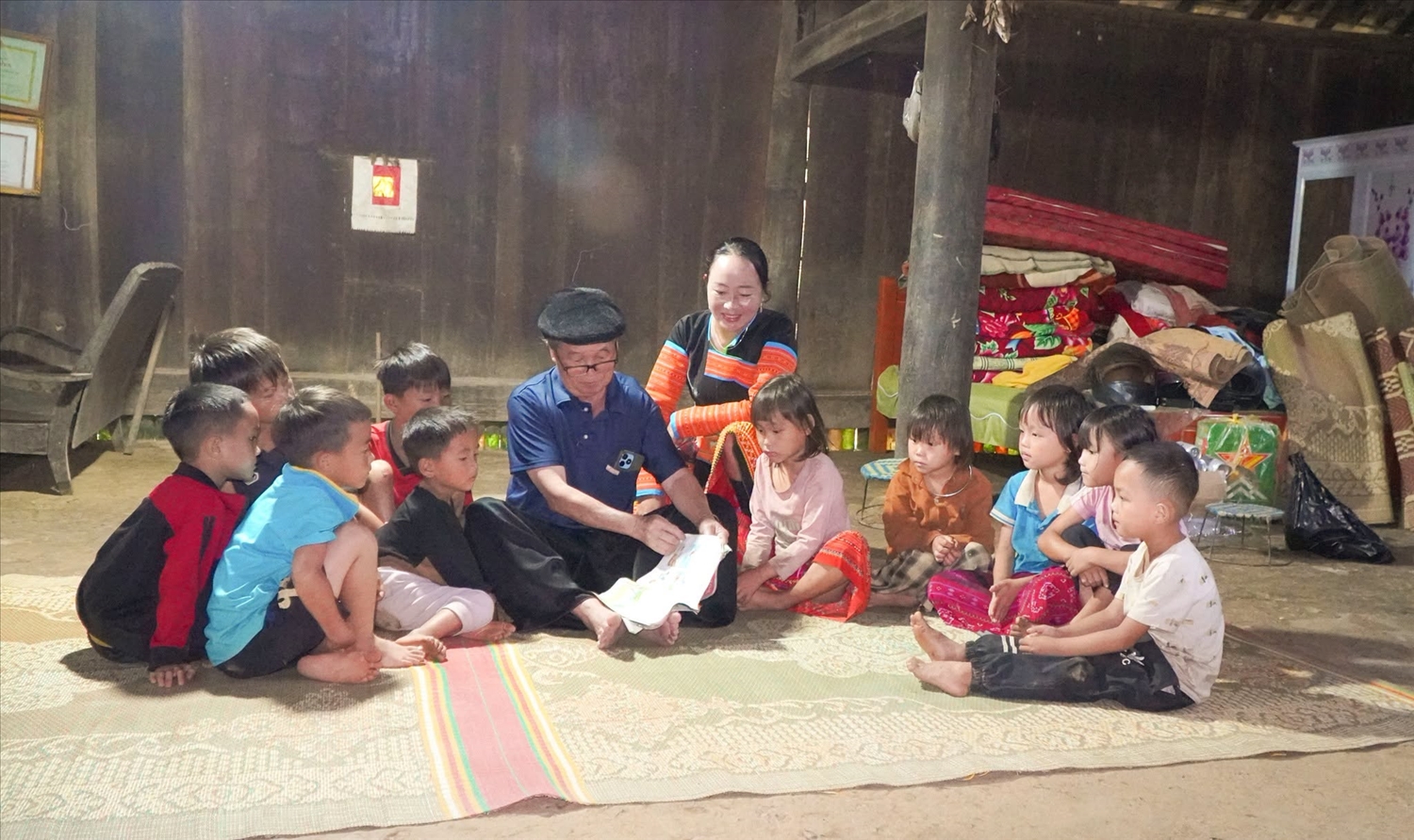 Ông Mùa A Chu, Người có uy tín ở bản Lọng Hỏm, xã Phiêng Cằm, hướng dẫn các em nhỏ đọc và tìm hiểu nội dung trong sách